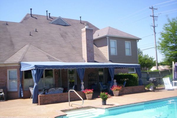 scalloped fabric awning with drop curtains over patio by swimming pool